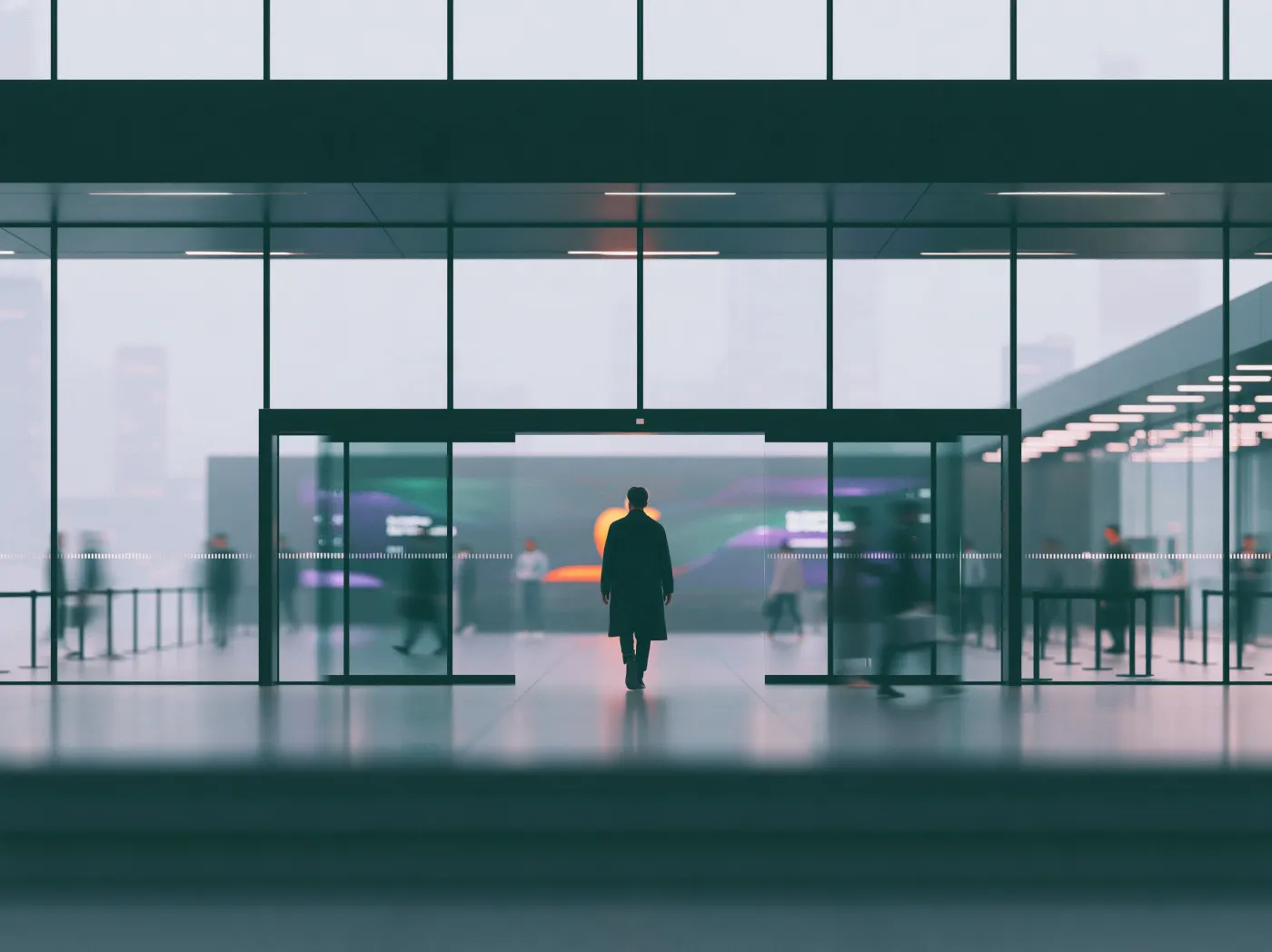 A modern lobby's glass doors sliding open as a person walks straight through